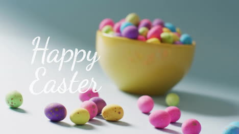 Animation-of-happy-easter-text-over-colourful-easter-eggs-in-bowl-on-blue-background
