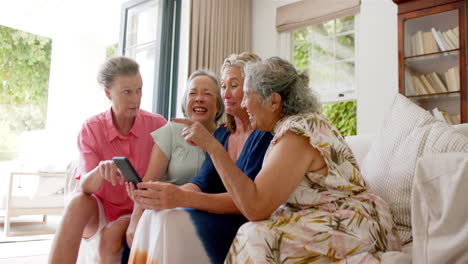Using-a-smartphone,-a-senior-diverse-group-of-women-share-a-moment-at-home