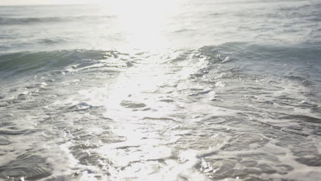 Sunlight-reflects-off-the-gentle-waves-at-the-beach,-creating-a-serene-atmosphere