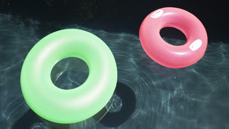 Two-colorful-swim-rings-float-on-a-pool's-surface