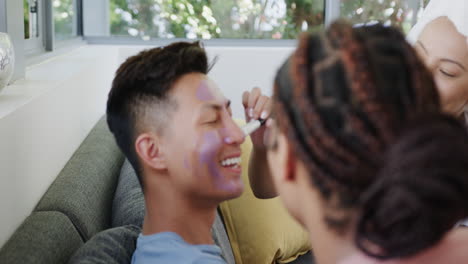 Young-Asian-man-enjoys-a-playful-moment-at-home-applying-a-face-mask