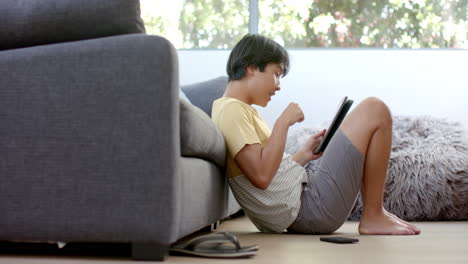 Teenage-Asian-boy-focused-on-his-tablet-at-home