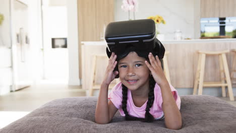 Biracial-girl-with-a-VR-headset-smiles-in-a-modern-living-room