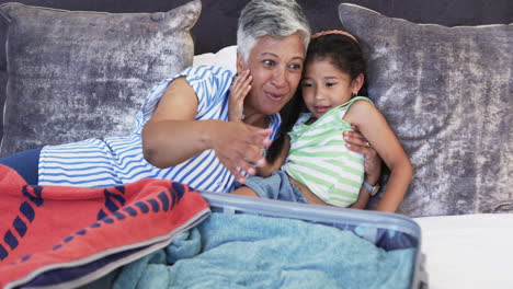 Biracial-woman-and-child-share-a-moment-on-a-couch,-woman-whispers-to-the-girl
