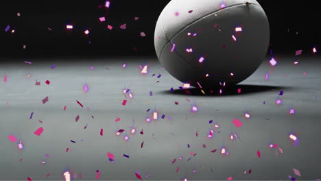 Animation-of-confetti-over-white-rugby-ball-on-black-background