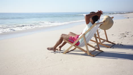 A-young-biracial-man-relaxes-on-a-beach-chair-by-the-sea-with-copy-space