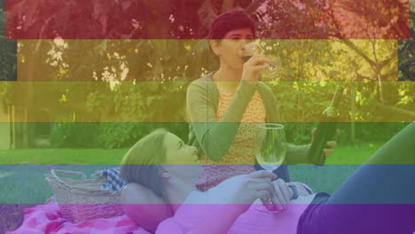 Animation-Von-Stolzen-Regenbogenstreifen-über-Einem-Glücklichen-Kaukasischen-Lesbischen-Paar,-Das-Im-Sonnigen-Garten-Wein-Trinkt