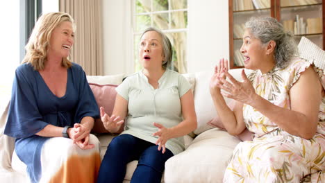 Three-senior-women-share-a-joyful-moment-on-a-couch-at-home