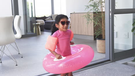 Biracial-girl-with-sunglasses-and-a-pink-swim-ring-prepares-for-pool-time