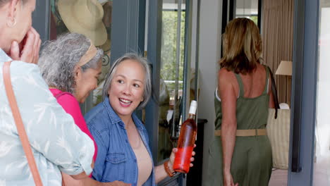 Senior-biracial-woman-greets-friends-at-her-home's-entrance