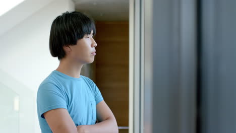 Teenage-Asian-boy-stands-thoughtfully-indoors,-with-copy-space