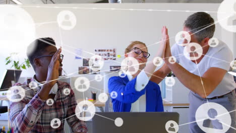 Animation-of-network-of-connections-with-icons-over-diverse-business-people-high-fiving-in-office