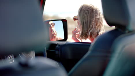 Caucasian-woman-checks-her-phone-in-a-car-on-a-road-trip