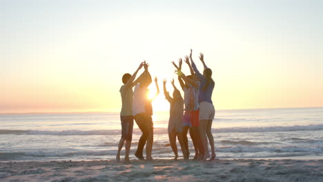 Eine-Bunt-Gemischte-Gruppe-Von-Freunden-Feiert-Bei-Sonnenuntergang-Eine-Party-Am-Strand