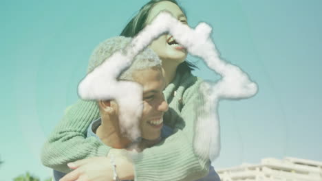 Animation-of-cloud-house-icon-over-happy-biracial-man-carrying-his-girlfriend-piggyback