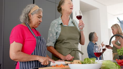 Ältere-Frau-Mit-Gemischter-Abstammung-Und-Kaukasische-Frau-Lachen-Gemeinsam,-Während-Sie-In-Der-Küche-Zu-Hause-Eine-Mahlzeit-Zubereitet