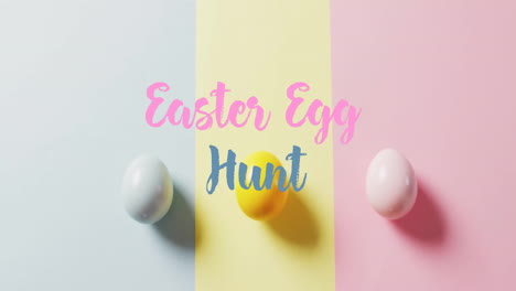 Animation-of-easter-egg-hunt-text-over-colourful-easter-eggs-on-blue,-yellow-and-pink-background