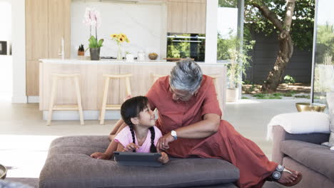 Biracial-grandmother-and-her-granddaughter-are-sharing-a-moment-in-a-modern-living-room