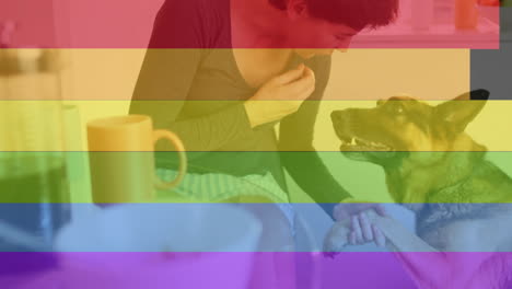 Animation-of-pride-rainbow-stripes-over-happy-caucasian-woman-and-pet-dog-in-kitchen