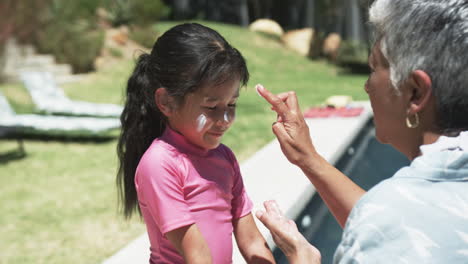 Biracial-man-applies-sunscreen-on-a-biracial-girl's-face-outdoors