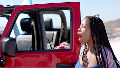 Young-African-American-woman-enjoys-a-sunny-day-by-the-beach-on-a-road-trip