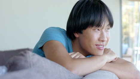 Smiling-teenage-Asian-boy-lounges-comfortably-at-home