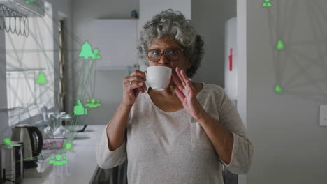 Animation-of-network-of-connections-with-icons-over-senior-african-american-woman-drinking-coffee