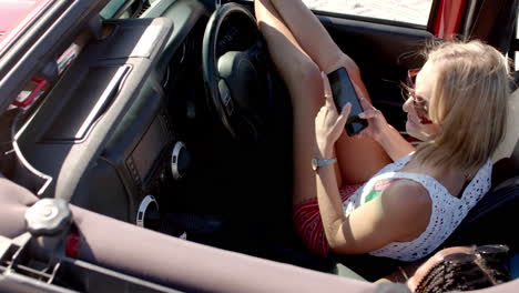 Young-Caucasian-woman-checks-her-phone-in-a-car-on-a-road-trip