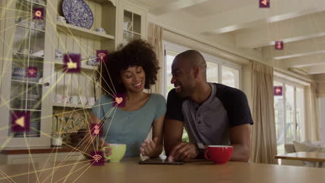 Animation-of-network-of-connections-with-icons-over-african-american-couple-drinking-coffee
