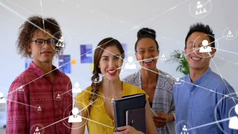Animation-of-network-of-connections-with-icons-over-diverse-business-people-smiling-in-office