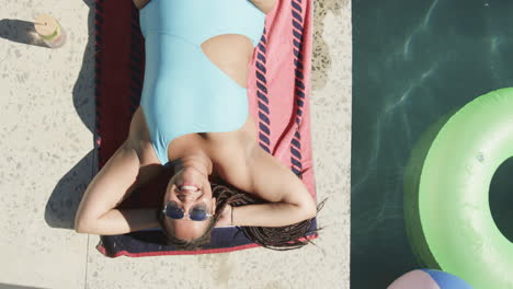 Young-biracial-woman-enjoys-sunshine-by-the-pool,-with-copy-space