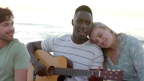 Young-African-American-man-plays-guitar-outdoors-at-a-beach-party