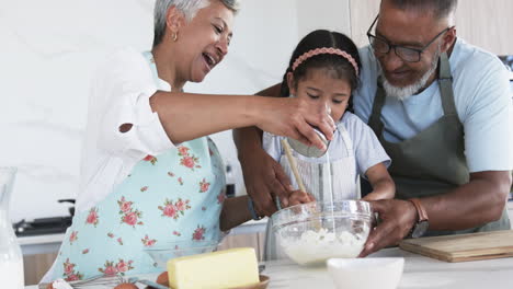 Biracial-grandparents-and-their-young-granddaughter-are-baking-together-in-a-kitchen