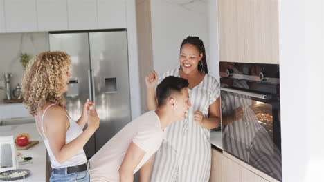 Young-Asian-man-and-biracial-women-share-a-laugh-in-a-modern-kitchen-while-making-pizza