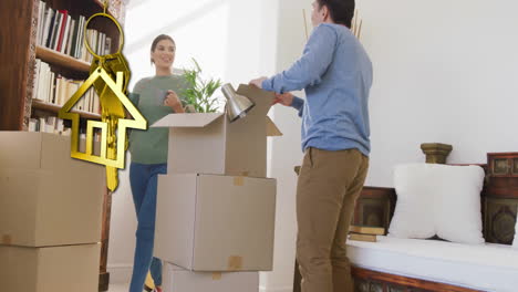 Animation-of-gold-house-key-and-key-fob-over-biracial-couple-unpacking-boxes-moving-in-new-home