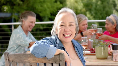 Senior-biracial-woman-enjoys-a-hearty-laugh-at-an-outdoor-gathering