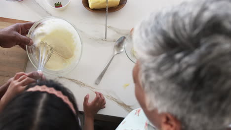 A-biracial-granddaughter-and-a-grandmother-with-grey-hair-are-baking-together