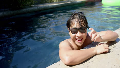 Teenage-Asian-boy-enjoys-a-sunny-day-at-the-pool,-with-copy-space