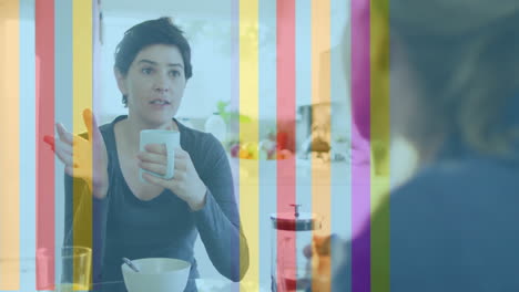 Animation-of-pride-rainbow-stripes-over-caucasian-lesbian-couple-talking-at-breakfast