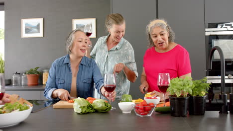 Caucasian-woman,-Asian-woman,-and-senior-biracial-woman-enjoy-a-home-cooking-session-preparing-a-mea