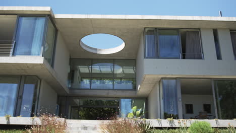 A-modern-house-features-large-glass-windows-and-a-distinctive-circular-opening