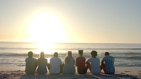 Diverse-group-of-friends-enjoy-a-serene-beach-sunset,-with-copy-space