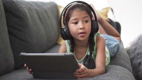 Biracial-girl-with-braided-hair-wearing-headphones-uses-a-tablet