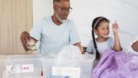 Biracial-grandfather-and-granddaughter-sort-recyclables-in-a-bright-kitchen