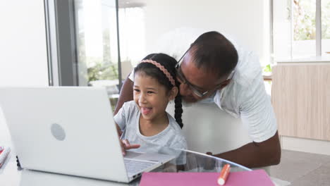 Biracial-grandfather-and-granddaughter-share-a-joyful-moment-over-a-laptop-at-home