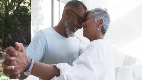 Biracial-couple-shares-a-tender-moment,-both-with-gray-hair-and-glasses