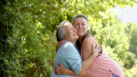 Senior-Caucasian-and-Asian-women-share-a-joyful-embrace-outdoors