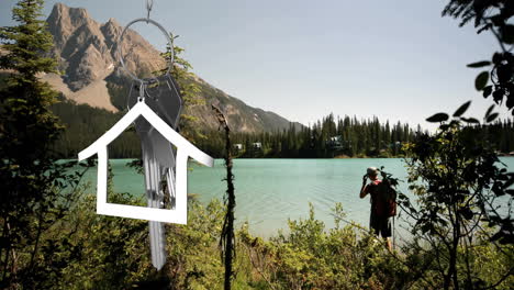 Animation-of-silver-house-and-key-over-caucasian-man-at-lake
