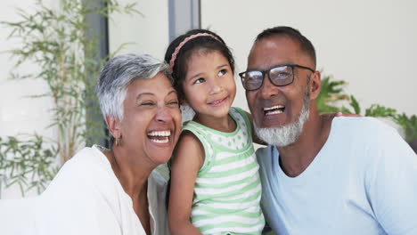 Biracial-girl-with-a-beaming-smile-is-flanked-by-her-joyful-grandparents