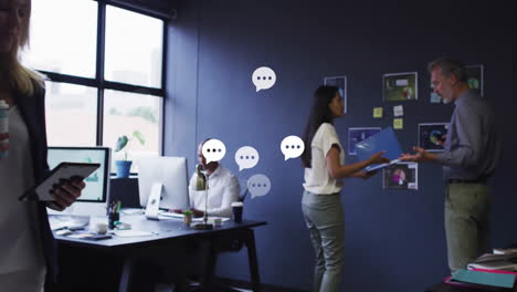 Animation-of-speech-bubbles-icons-over-diverse-colleagues-working-in-office